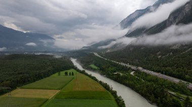 Haiming, Tyrol yakınlarındaki Avusturya Alpleri 'ndeki yeşil vadi ve otobanda akan Inn nehrinin hava manzarası dramatik fırtınalı gökyüzünün altında.