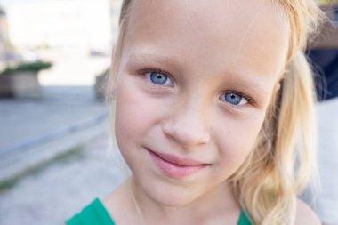 Parlak mavi gözlü sarışın çocuk, saf mutluluğu ve gençlik cazibesini yansıtıyor.