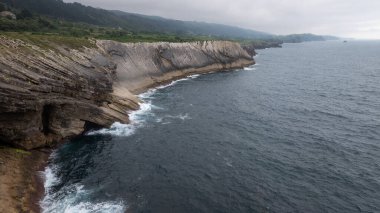Bulutlu bir günde engebeli kayalıklara çarpan dramatik dalgalar İspanya 'nın Asturias kentinde güçlü bir deniz manzarası yaratıyor.
