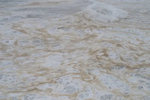 Hava deniz manzarası, kumlu kıyı şeridine karşı kırılan okyanus dalgalarının ritmik beyaz köpük desenleri oluşturduğunu gösteriyor.