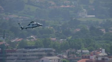 GIJON, SPAIN - 27 Temmuz 2025: Devriye uçuşu sırasında sivil EC135 helikopteri konut alanı üzerinde alçaktan uçuyordu