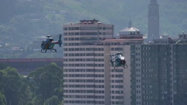 GIJON, SPAIN - 27 Temmuz 2025: 2 İspanyol EC120 Colibri helikopteri uçuş sırasında şehir binalarının üzerinde uçuyor.