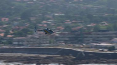 GIJON, İSPAN - 27 Temmuz 2025: İspanyol EC120 Colibri helikopteri Gijon 'daki uçak gösterisi sırasında şehir binaları üzerinde alçaktan uçuyordu