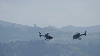 GijON, İSPAN - 27 Temmuz 2025: Gijon yakınlarındaki tepe üzerinde uçan iki EC120 Colibri helikopteri