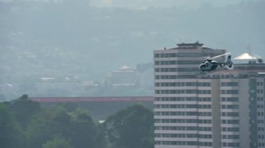 Polis helikopteri alçak irtifada yüksek binaları geçiyor.