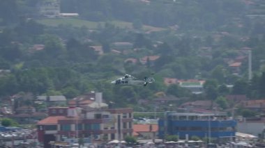 Kamu etkinliği sırasında sahil kenarındaki binaların üzerinde alçak irtifada uçan polis helikopteri.