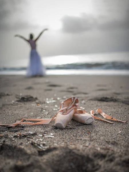 Pointe shoes on the sand , a ballerina in the background