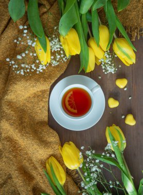 Beyaz arka planda sarı laleler çerçevesinde bir kahve fincanı. Düz yatıyordu, üstten bak. Tatil kavramı, doğum günü, Paskalya, 8 Mart.
