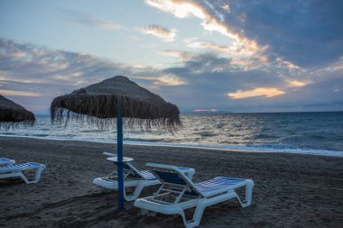 İspanya, Almerya 'da güneşlenen bir yatakla kumsalda gün doğumu