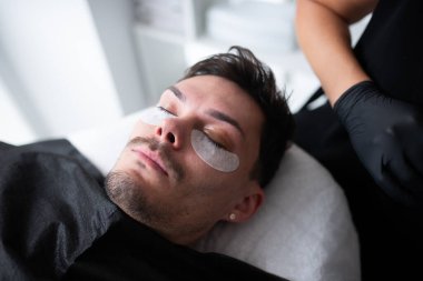 Güzellik salonunda kirpik uzatmaya hazırlanan bir adam..