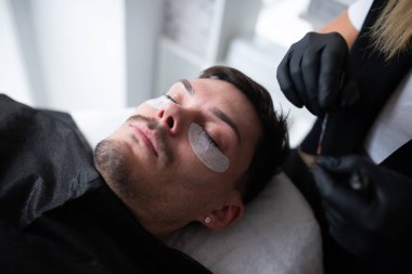 Güzellik salonunda kirpiklerle ilgilenen genç bir adam..