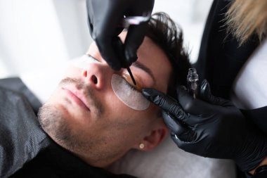 Güzellik salonunda kirpiklerle ilgilenen genç bir adam..