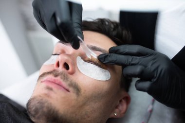 Güzellik salonunda kirpiklerle ilgilenen genç bir adam..