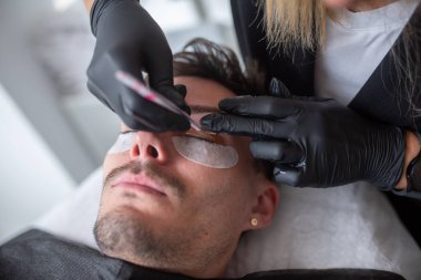 Güzellik salonunda kirpiklerle ilgilenen genç bir adam..