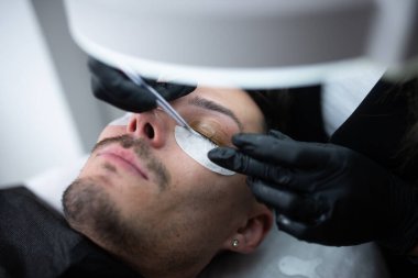 Güzellik salonunda kirpiklerle ilgilenen genç bir adam..