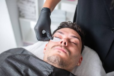 Güzellik salonunda kirpiklerle ilgilenen genç bir adam.