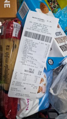 Bir el, bir markette paketlenmiş gıda malzemelerinin üzerinde dinlenirken bir market fişi tutuyor. Roquetas de Mar, Almerya, Endülüs, İspanya, 21 Mayıs 2025-