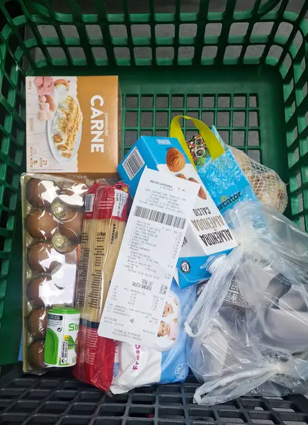 Bir el, bir markette paketlenmiş gıda malzemelerinin üzerinde dinlenirken bir market fişi tutuyor. Roquetas de Mar, Almerya, Endülüs, İspanya, 21 Mayıs 2025