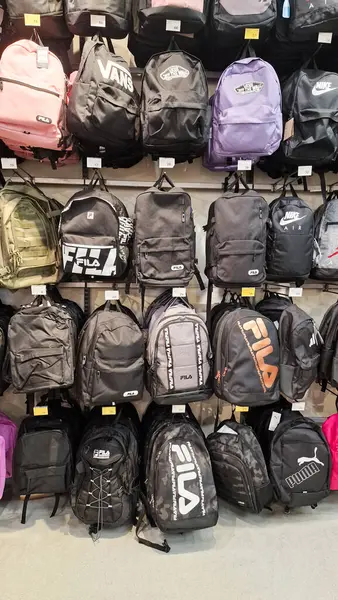 Almeria, İspanya - Haziran 02, 2025: Fila ve Puma gibi markaların moda siyah sırt çantalarının perakende duvarında sergilenmesi, öğrenciler ve moda severler için mükemmel