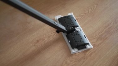 Steam mop moves smoothly across wooden floor, releasing steam to sanitize and clean surface, demonstrating effective home cleaning techniques and modern cleaning tools