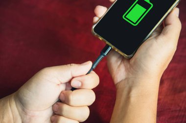 Close up a hands man unpluged the charging cable wrongly from smart phone on a table