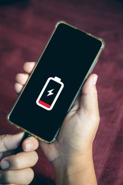 Masadaki akıllı bir telefona şarj aleti takan bir adamın ellerini kapat.