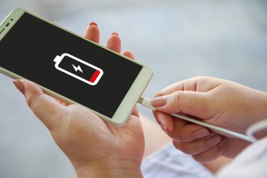 Akıllı telefonunu şarj eden bir kadının ellerini kapat.