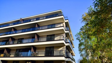 Yeşil yerleşim bölgesinde yeni daireleri olan modern bir yerleşim yeri. Yeşil ağaç ve yeni apartman. Doğanın ve modernliğin ahengi. Daire yeni sakinleri bekliyor..