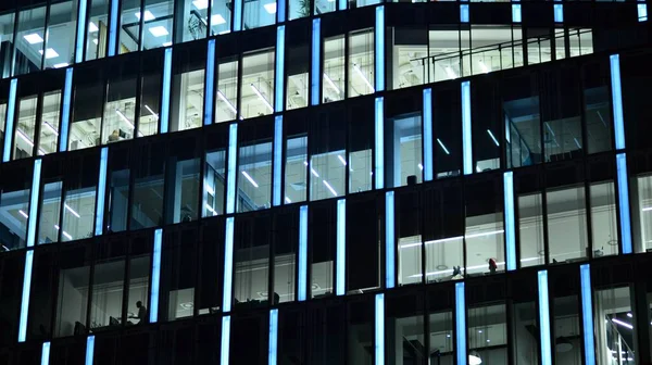 stock image Modern office building in city at the night. View on illuminated offices of a corporate building. Blinking light in window of the multi-storey building of glass and steel. Long exposure at night