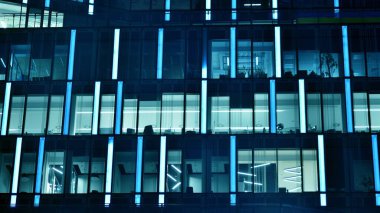 Ofis binalarının pencereleri gece aydınlandı. Cam mimari, geceleri şirket binası, iş konsepti. Mavi grafik filtresi.