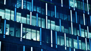 Ofis binalarının pencereleri gece aydınlandı. Cam mimari, geceleri şirket binası, iş konsepti. Mavi grafik filtresi.