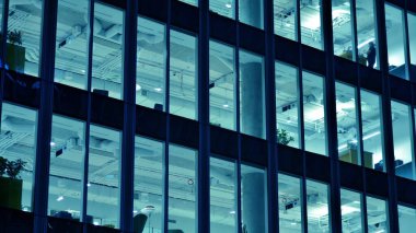 Ofis binalarının pencereleri gece aydınlandı. Cam mimari, geceleri şirket binası, iş konsepti. Mavi grafik filtresi.