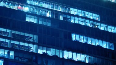 Ofis binalarının pencereleri gece aydınlandı. Cam mimari, geceleri şirket binası, iş konsepti. Mavi grafik filtresi.