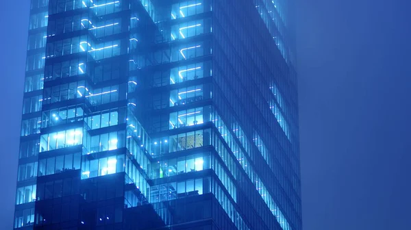 办公大楼的窗户在夜间照明 玻璃建筑 公司建筑在夜间营业的概念 蓝色图形滤波器 — 图库照片