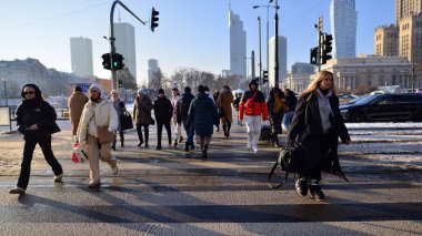 Varşova, Polonya. 14 Aralık 2022. Büyük bir şehrin kış caddesi. Farklı yaşlarda insanlar karşıdan karşıya geçiyor. Şehir caddesi manzarası sakinleri, turistler ve modern binalar.   