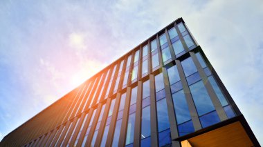 Mavi gökyüzü arka planlı cam modern bina. Düşük açı ve mimari detaylar. Şehir soyutu - güneş ışığında cam ofis binasının pencereleri.