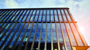 Mavi gökyüzü arka planlı cam modern bina. Düşük açı ve mimari detaylar. Şehir soyutu - güneş ışığında cam ofis binasının pencereleri.