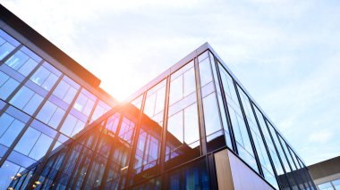 Mavi gökyüzü arka planlı cam modern bina. Düşük açı ve mimari detaylar. Şehir soyutu - güneş ışığında cam ofis binasının pencereleri.