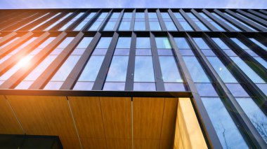 Mavi gökyüzü arka planlı cam modern bina. Düşük açı ve mimari detaylar. Şehir soyutu - güneş ışığında cam ofis binasının pencereleri.