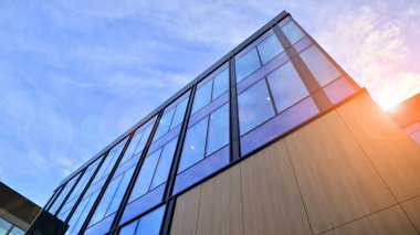 Mavi gökyüzü arka planlı cam modern bina. Düşük açı ve mimari detaylar. Şehir soyutu - güneş ışığında cam ofis binasının pencereleri.