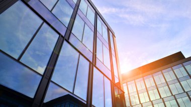 Mavi gökyüzü arka planlı cam modern bina. Düşük açı ve mimari detaylar. Şehir soyutu - güneş ışığında cam ofis binasının pencereleri.