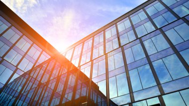 Mavi gökyüzü arka planlı cam modern bina. Düşük açı ve mimari detaylar. Şehir soyutu - güneş ışığında cam ofis binasının pencereleri.