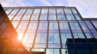 Mavi gökyüzü arka planlı cam modern bina. Düşük açı ve mimari detaylar. Şehir soyutu - güneş ışığında cam ofis binasının pencereleri.