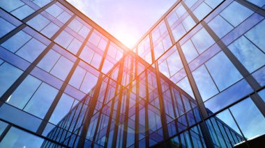 Mavi gökyüzü arka planlı cam modern bina. Düşük açı ve mimari detaylar. Şehir soyutu - güneş ışığında cam ofis binasının pencereleri.