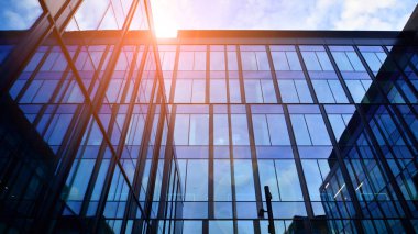 Mavi gökyüzü arka planlı cam modern bina. Düşük açı ve mimari detaylar. Şehir soyutu - güneş ışığında cam ofis binasının pencereleri.