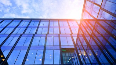 Mavi gökyüzü arka planlı cam modern bina. Düşük açı ve mimari detaylar. Şehir soyutu - güneş ışığında cam ofis binasının pencereleri.