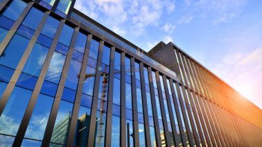 Mavi gökyüzü arka planlı cam modern bina. Düşük açı ve mimari detaylar. Şehir soyutu - güneş ışığında cam ofis binasının pencereleri.