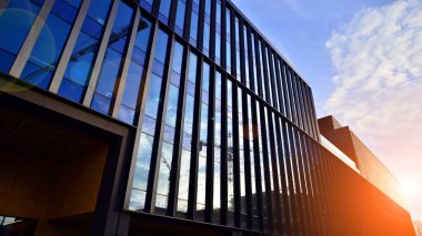 Mavi gökyüzü arka planlı cam modern bina. Düşük açı ve mimari detaylar. Şehir soyutu - güneş ışığında cam ofis binasının pencereleri.