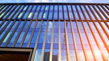 Mavi gökyüzü arka planlı cam modern bina. Düşük açı ve mimari detaylar. Şehir soyutu - güneş ışığında cam ofis binasının pencereleri.