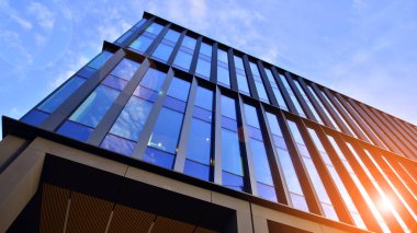 Mavi gökyüzü arka planlı cam modern bina. Düşük açı ve mimari detaylar. Şehir soyutu - güneş ışığında cam ofis binasının pencereleri.